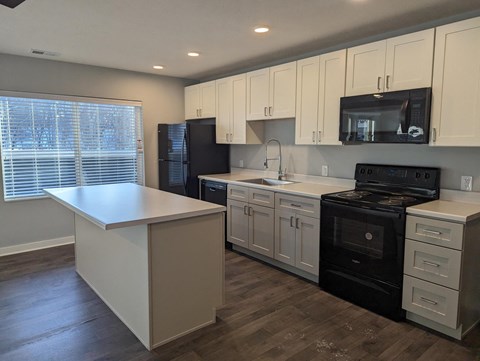a kitchen with white cabinets and black appliances